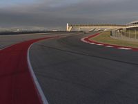 a track that has a red line going around it near a building with a view on a cloudy sky