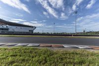 the racetrack at a track with green grass and grass around it in front of a light pole