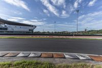 the racetrack at a track with green grass and grass around it in front of a light pole