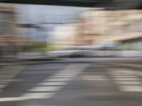 a blurry photo shows an intersection and a car passing under an overpass on the street