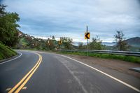 a curve in the road that leads down the side of a hill on a rainy day