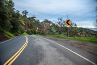 a curve in the road that leads down the side of a hill on a rainy day