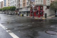 a wet city street with a red building and cars on it on a rainy day