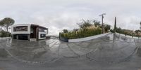 a fisheye photograph of a street corner on a rainy day with chains and buildings