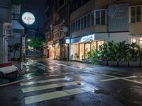 wet street on a rainy evening with traffic passing by at night, lit up by shop signs