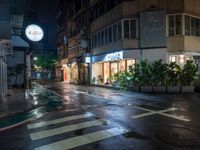 wet street on a rainy evening with traffic passing by at night, lit up by shop signs