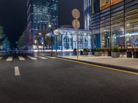 a night time view of a bus stop and street with illuminated buildings in the background