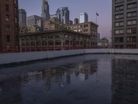 city buildings reflecting in the water on a rainy day with purple skies above them and city streets reflected in wet puddles of water