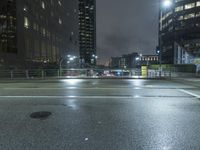 a rainy, wet street at night with a blue traffic light in the distance from a pedestrian crossing