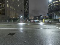 a rainy, wet street at night with a blue traffic light in the distance from a pedestrian crossing