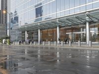 people walking on the sidewalk outside the building with reflections in the windows of it,
