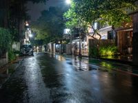 an empty street with rain on the side and cars parked on either side of it