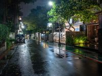 an empty street with rain on the side and cars parked on either side of it