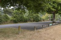 a bench sitting next to the side of the road in a field next to some trees