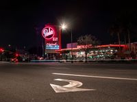 a sign and cars parked outside the building that looks like the hotel called red barn in las angeles