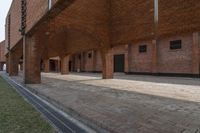 red brick building with arched windows on side and green grass under ground area with steps