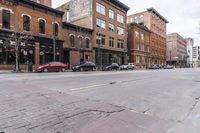 a group of cars parked outside a red brick building and a red car in front of it