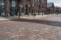 a building that has people walking on the sidewalk in front of it is red bricks