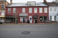 a large red brick building has a lot of windows and shutters with awnings