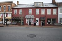 a large red brick building has a lot of windows and shutters with awnings