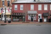 a large red brick building has a lot of windows and shutters with awnings