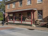 a small red brick store front on a street corner with benches and benches in the sidewalk