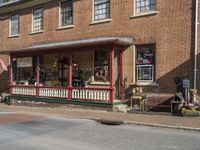 a small red brick store front on a street corner with benches and benches in the sidewalk