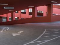 the back end of a red building with red and white painted lines on it, in the parking lot