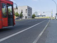 red bus in motion on street next to modern building in city skyline area with urban buildings