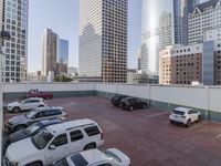 the red car is parked in the empty lot by the street with tall buildings behind it