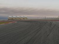 the red car is racing along a paved track as the clouds hang over the area