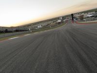 the red car is racing along a paved track as the clouds hang over the area