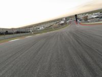 the red car is racing along a paved track as the clouds hang over the area