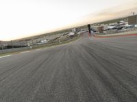 the red car is racing along a paved track as the clouds hang over the area