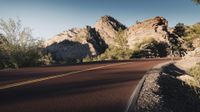 there is a red car on the side of the road with mountains in the background