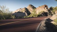 there is a red car on the side of the road with mountains in the background