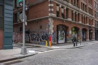 an empty bricked sidewalk in the city of new york city with a red fire hydrant and a brick building with a large doorway