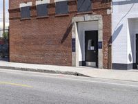 a red fire hydrant next to a brick building on the corner of a street