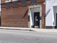 a red fire hydrant next to a brick building on the corner of a street