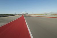 a motorcyclist rides the red line of a road, as viewed from the perspective of the driver