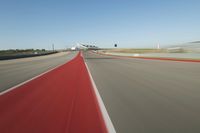 a motorcyclist rides the red line of a road, as viewed from the perspective of the driver