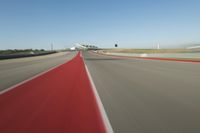 a motorcyclist rides the red line of a road, as viewed from the perspective of the driver