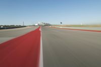 a motorcyclist rides the red line of a road, as viewed from the perspective of the driver