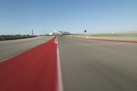 a motorcyclist rides the red line of a road, as viewed from the perspective of the driver