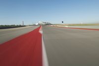 a motorcyclist rides the red line of a road, as viewed from the perspective of the driver