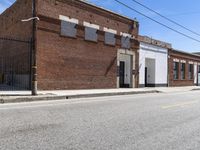 a red motorcycle sitting outside an old, run down building with a street behind it