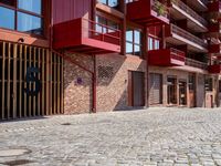 a red motorcycle parked next to a brick paved sidewalk and buildings that have balconies