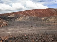 a red colored mountain with many rocks, gravel and dirt scattered in the ground below