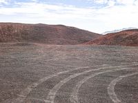 a big red mountain with tracks in the middle and dirt around it on the side of a hill