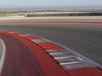 an empty track at a motorsports club with some red and white stripeing on it